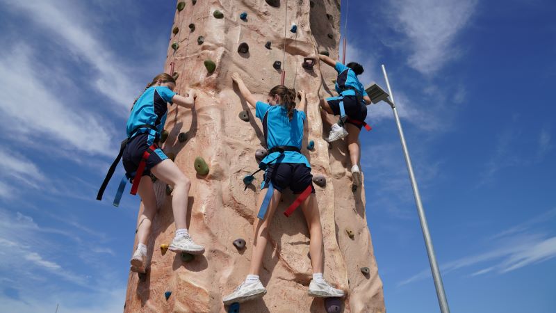 School girls climbing a rock tower