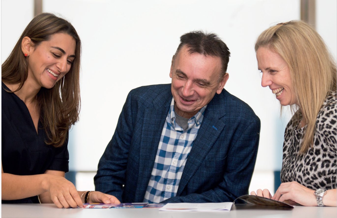 Women and Man sitting at table looking at documents