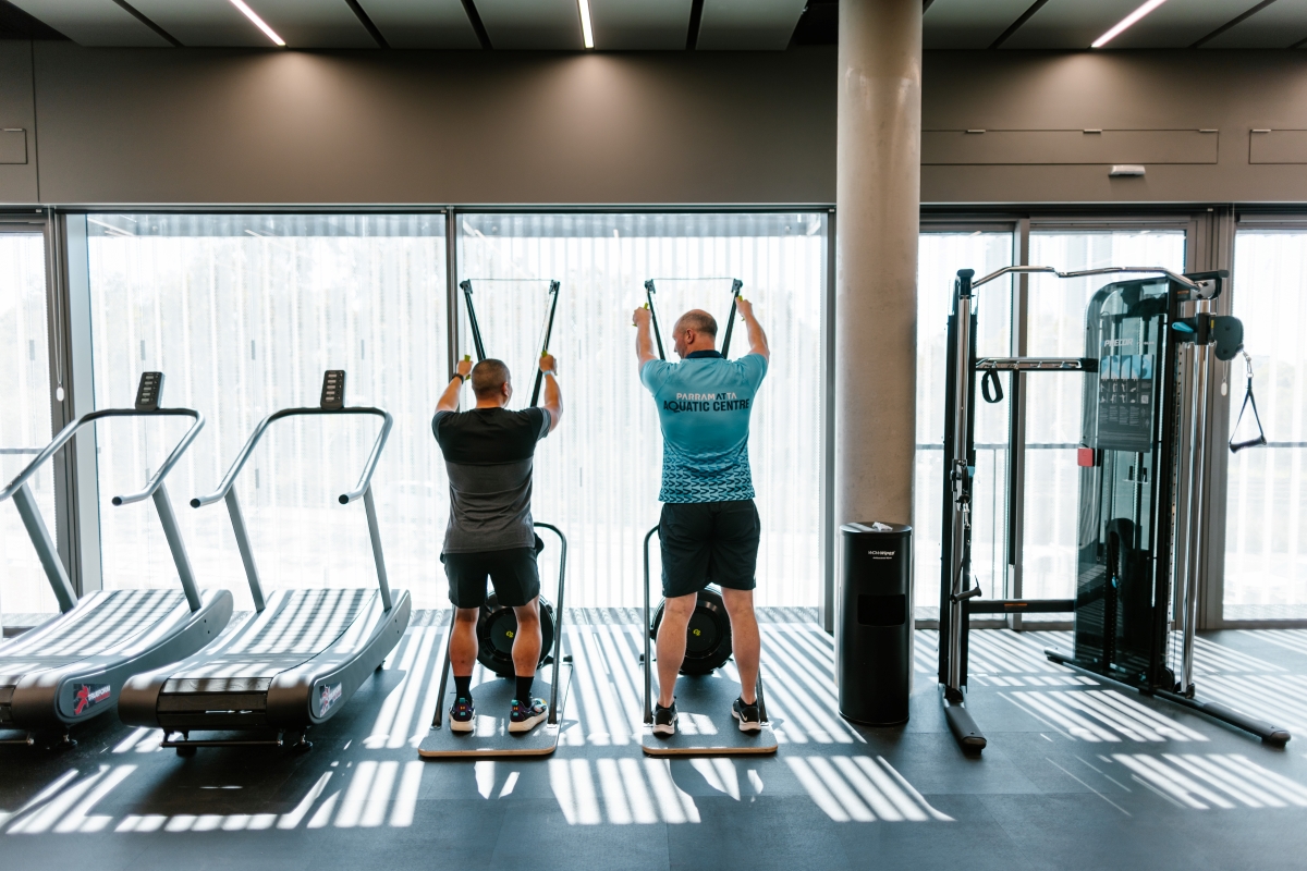 Two men from behind using gym equiment