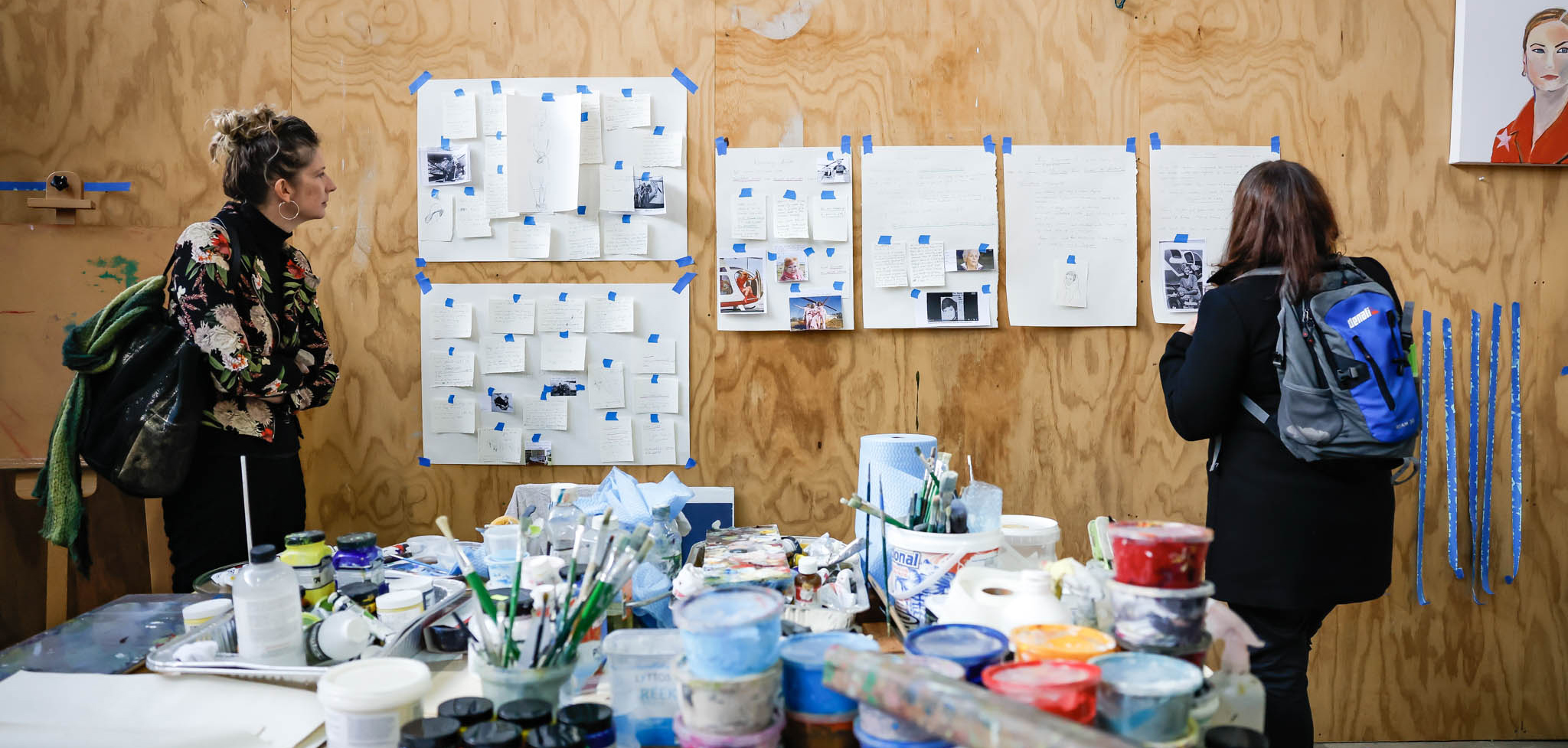 Two people in a studio filled with art supplies